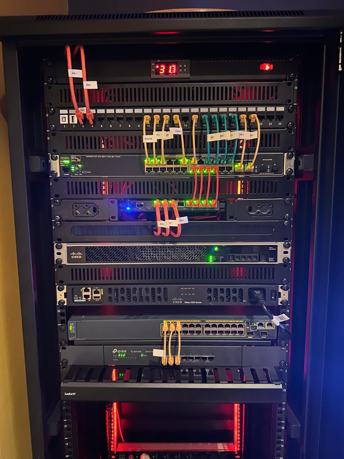 The home-lab rack: patch panel, HPE Aruba switch, Cisco ASA and ISR 4300 with structured cabling